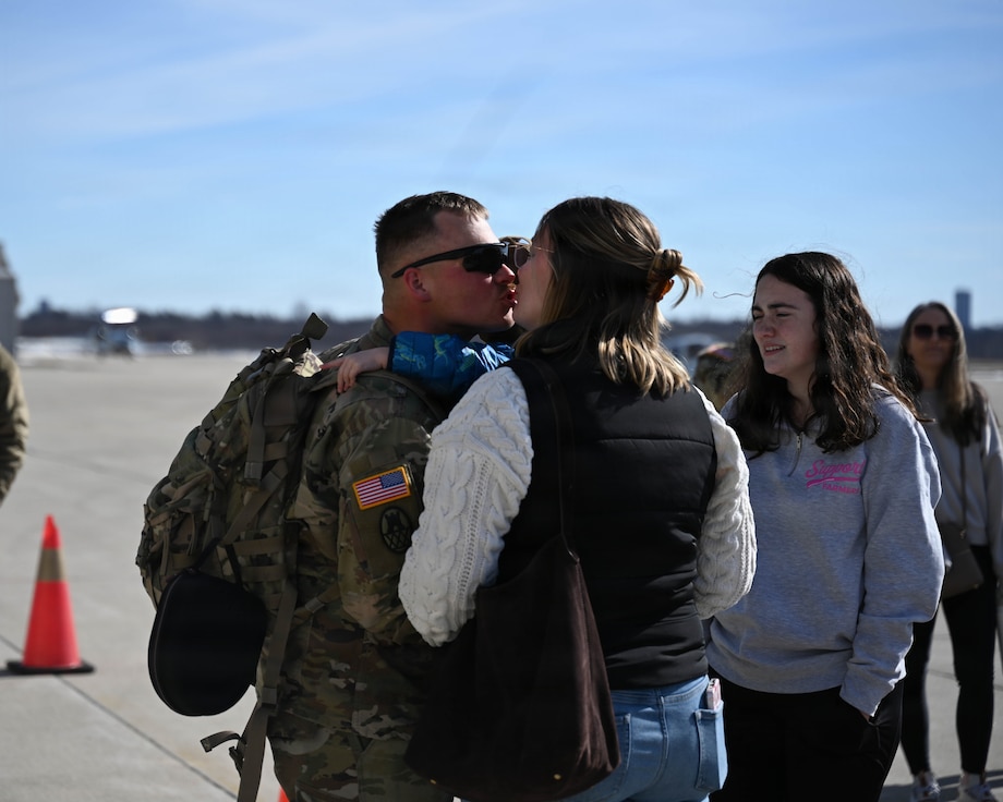 Illinois Army National Guard Cpl. Briar Ricketts holds his 3-year-old son, Maverick Ricketts, and kisses his mother, Elizabeth Ricketts.