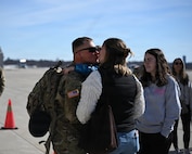 Illinois Army National Guard Cpl. Briar Ricketts holds his 3-year-old son, Maverick Ricketts, and kisses his mother, Elizabeth Ricketts.