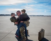 Illinois Army National Guard Chief Warrant Officer 2 Chris Burbach embraces his sons, Tommy and Danny, after returning home from deployment.