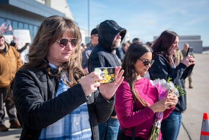 Family members and friends of soldiers from the 661st Engineer Construction Company take photos and videos of the soldiers returning from deployment during a homecoming event.