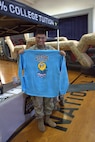 Pfc. Alex Torres poses with a shirt that is being handed out at the Sycamore Armory.