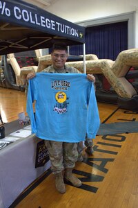 Pfc. Alex Torres poses with a shirt that is being handed out at the Sycamore Armory.