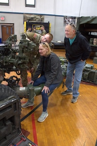 Sgt 1st Class James Nelson explains to his parents how to read the changes made when moving the tube on the M119A3 howitzer at the Sycamore Armory.