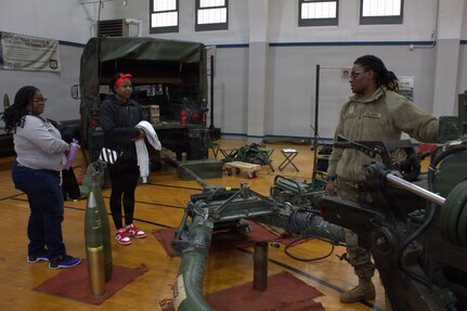 Pvt. Saniya Buchanan explains the operation of the M119A3 Howitzer to Destiny Walker (left) and Jordan Henderson (center) at the Sycamore Armory.