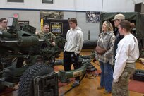 Sgt. Patrick Stockhausen explains the operations of an M119A3 Howitzer to members of the Riddle family at the Sycamore Armory.