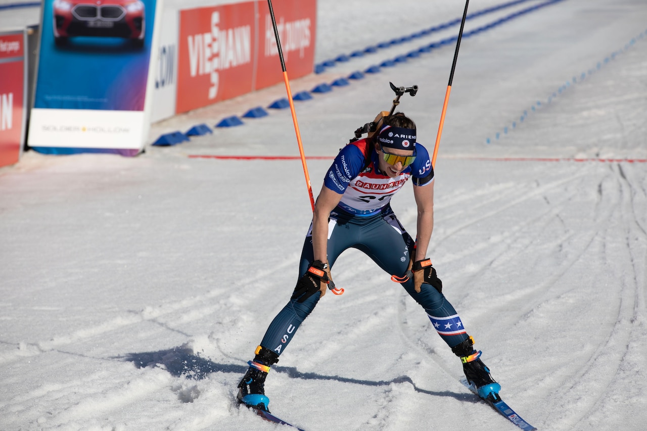 A woman wearing goggles and ski sports gear holds ski poles while skiing down a snowy slope.