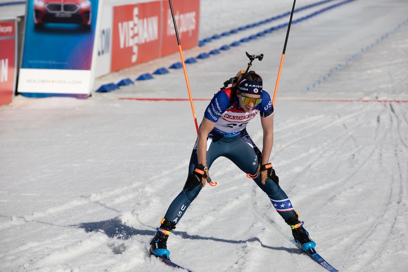 A woman wearing goggles and ski sports gear holds ski poles while skiing down a snowy slope.