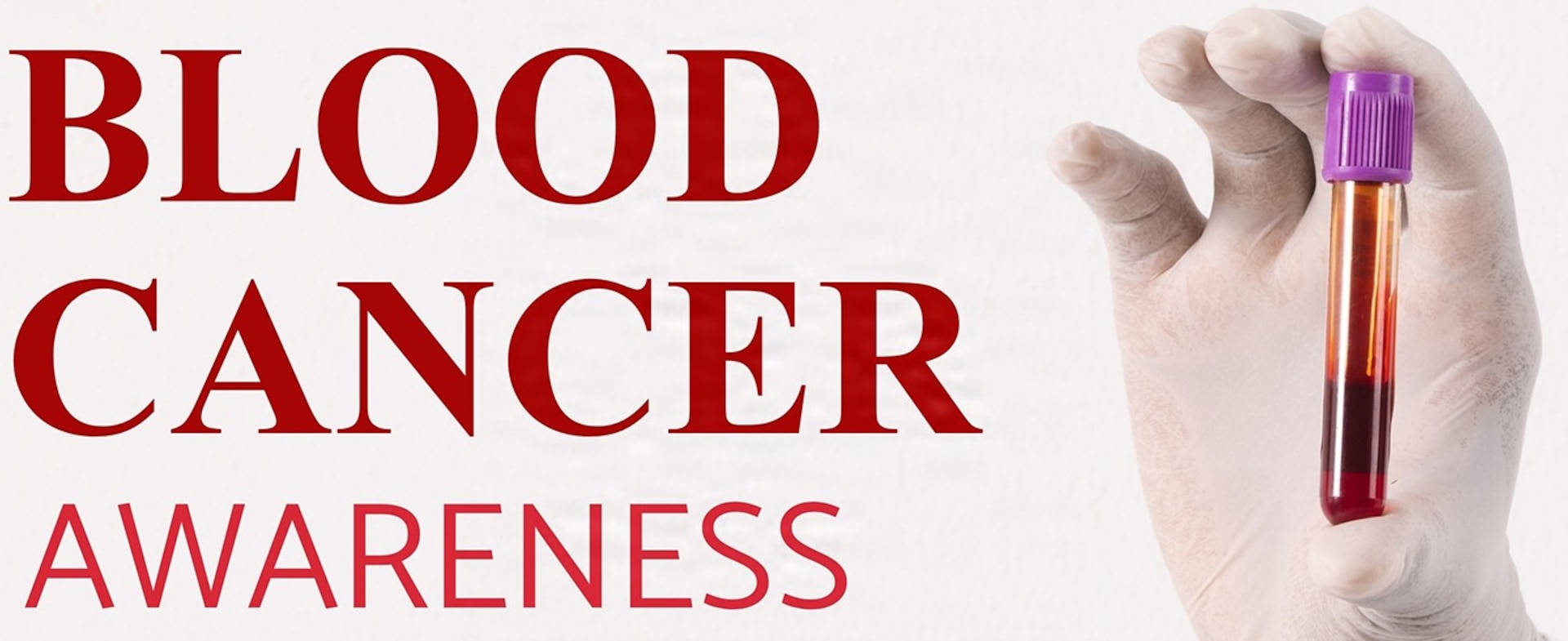 Hand holding a tube of blood.