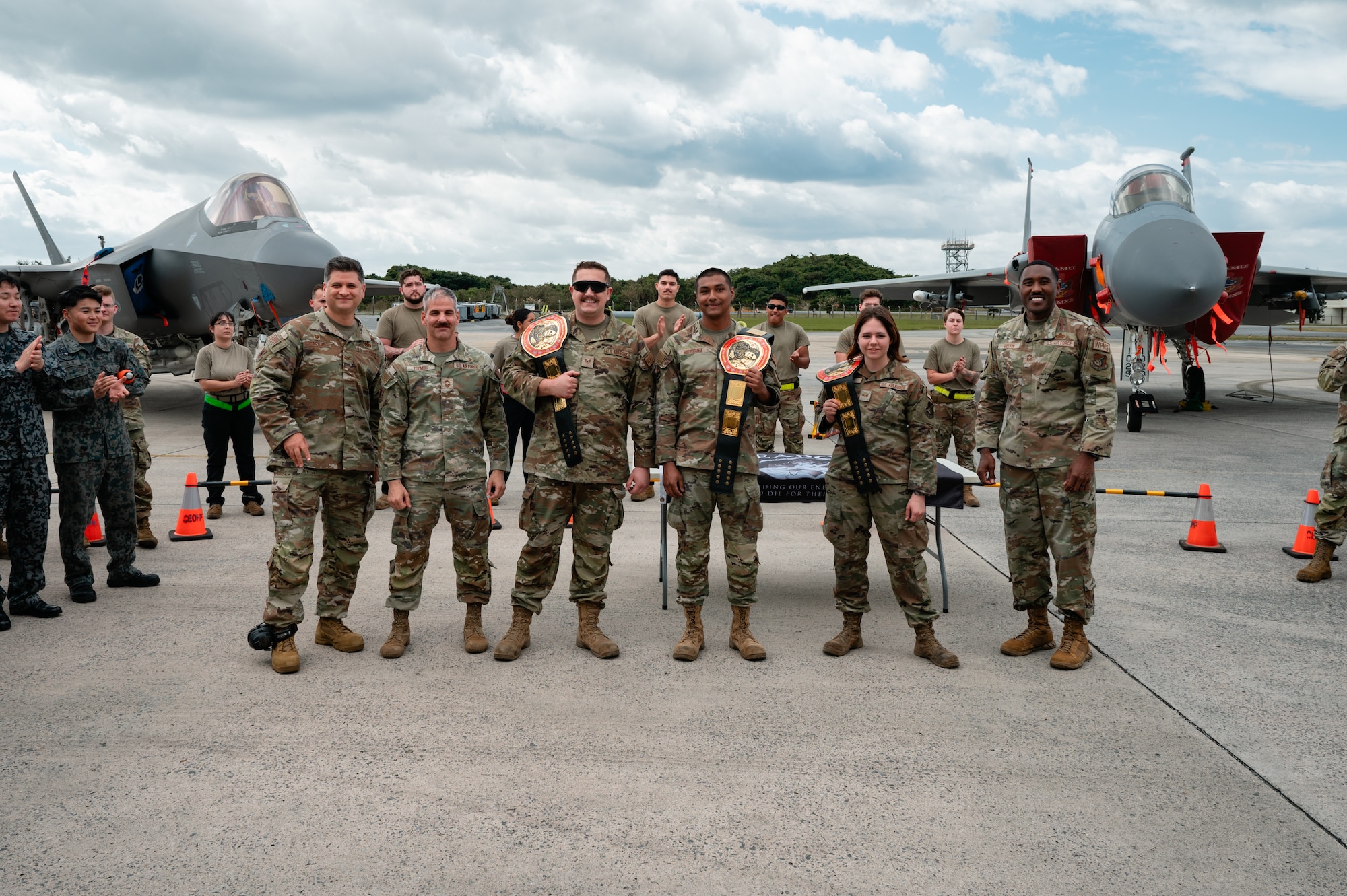 U.S. Air Force Col. Gerard Carisio, left, 18th Maintenance Group commander, Chief Master Sgt. James Toombs, 18th Maintenance Group superintendent, and Chief Master Sgt. Arthur Belvin, right, 18th Maintenance Group wing weapons manager, poses for a photo with the winning load crew members following the 18th Wing Load Crew of the Quarter Competition at Kadena Air Base, Japan, Jan. 30, 2025. The 18th Maintenance Group hosts weapons load competitions quarterly to enhance mission readiness and strengthen global strike capabilities. (U.S. Air Force photo by Airman 1st Class Francisco Huerta)