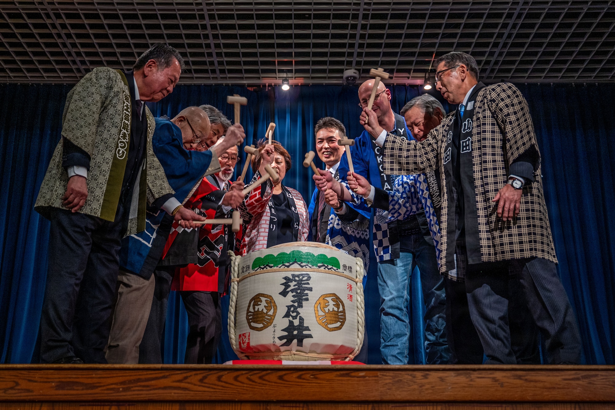 A group of people holding mallets surrounding a barrel