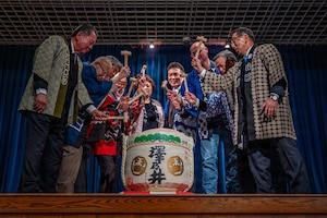 A group of people holding mallets surrounding a barrel