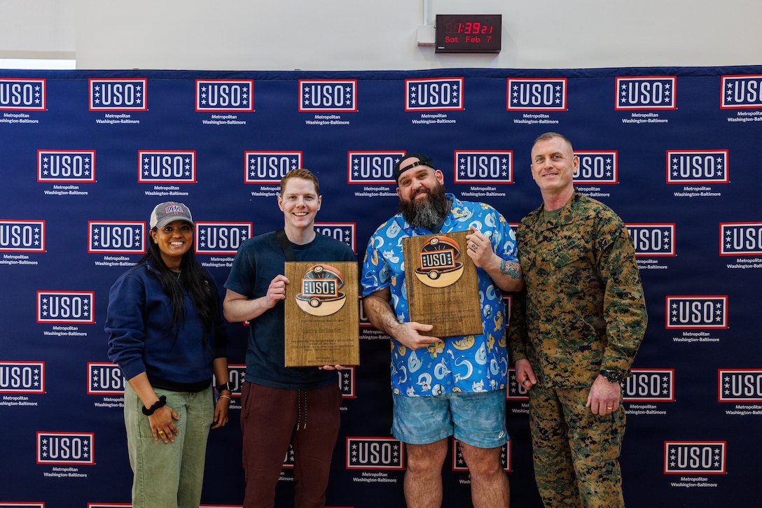 Taisha Jacobs Marine Corps Base Quantico’s United Service Center Operations specialist, left, and Sgt. Maj. Liam Williams, the Base Sergeant Major of Marine Corps Base Quantico, right, present awards to Ross Cooper the owner of Coops Collection. middle-left, and Phill Faust the owner of Beard Dad Cardz for their participation in the USO’s National Pokémon Day event held at the Quantico Middle/Highschool on Marine Corps Base Quantico, Feb. 7, 2026. This event was held to bring the community of MCB Quantico together with events including a scavenger hunt, card buying, battles and trading and a raffle. (U.S. Marine Corps photo by Lance Cpl. Donovan E. Melendez)
