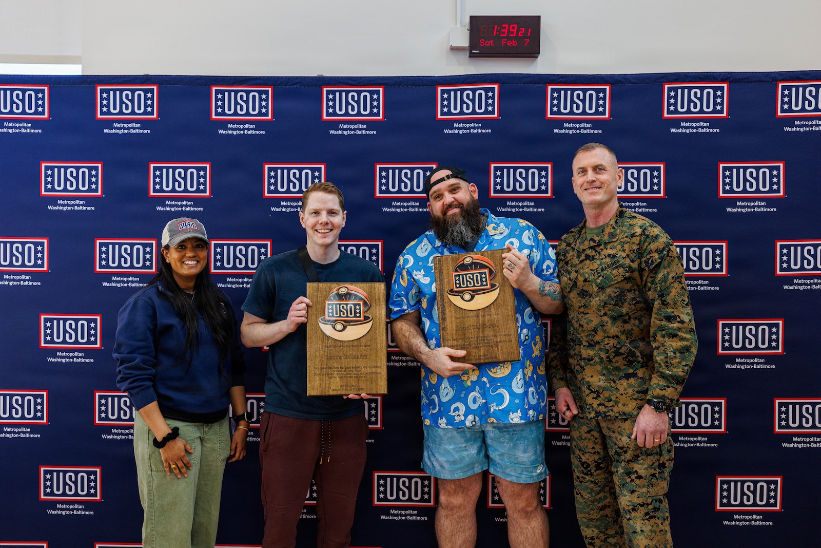 Taisha Jacobs Marine Corps Base Quantico’s United Service Center Operations specialist, left, and Sgt. Maj. Liam Williams, the Base Sergeant Major of Marine Corps Base Quantico, right, present awards to Ross Cooper the owner of Coops Collection. middle-left, and Phill Faust the owner of Beard Dad Cardz for their participation in the USO’s National Pokémon Day event held at the Quantico Middle/Highschool on Marine Corps Base Quantico, Feb. 7, 2026. This event was held to bring the community of MCB Quantico together with events including a scavenger hunt, card buying, battles and trading and a raffle. (U.S. Marine Corps photo by Lance Cpl. Donovan E. Melendez)