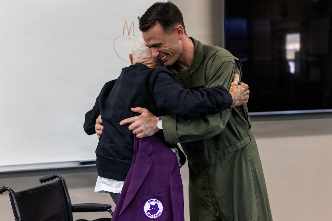 U.S. Marine Corps Lt. Col. Bunce, commanding officer of Marine Medium Tiltrotor Squadron (VMM) 364, Marine Aircraft Group 39, 3rd Marine Aircraft Wing, hugs U.S. Marine Corps veteran, Capt. Nelson J. Baker, after Baker received an honorary Purple Foxes jacket at Marine Corps Air Station Camp Pendleton, California, Jan. 30, 2026. Baker is a plank holder of VMM-364 and served as one of the squadron’s first pilots when it was commissioned as Marine Medium Helicopter Squadron (HMM) 364 in 1961. He visited to share the squadron’s legacy with the current generation of Marines who work with and fly the MV-22B Osprey. (U.S. Marine Corps photo by Lance Cpl. Jonathan Sherchand)