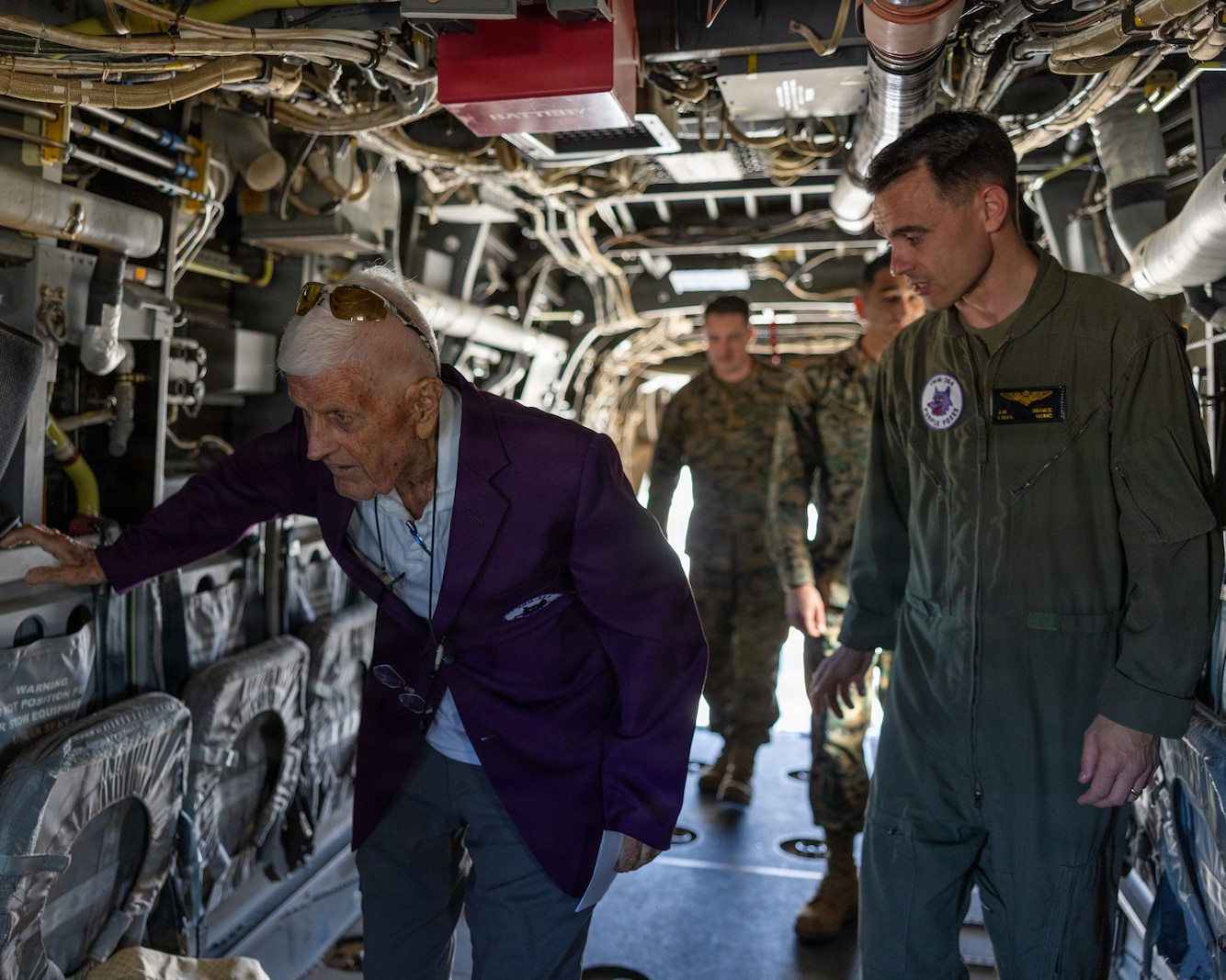 Marine Corps veteran Nelson Baker tours the inside of an MV-22B Osprey aircraft with active-duty Marines in camouflage utilities. 
