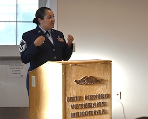 A woman in an Air Force dress uniform is at a podium addressing an audience