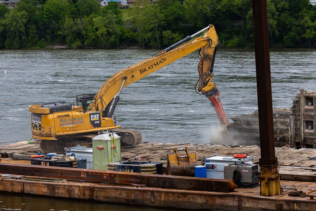 A construction drill demolishes a lock approach wall.