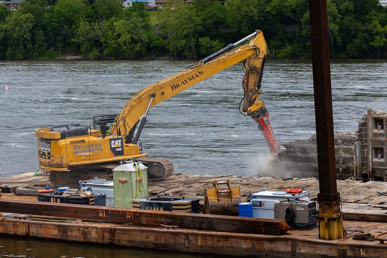 A construction drill demolishes a lock approach wall.