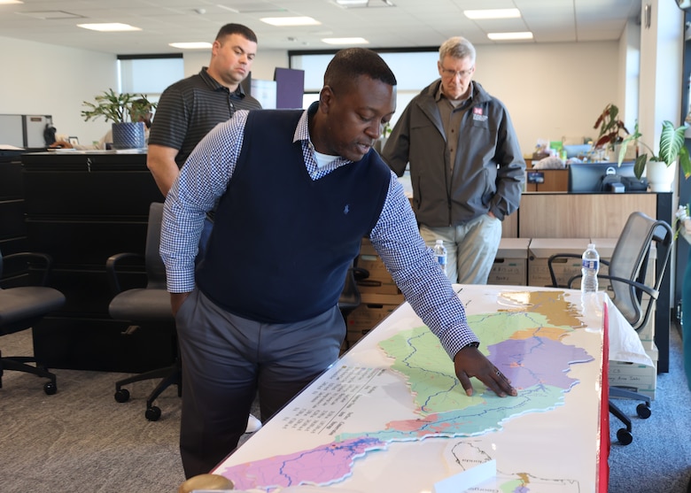 One man pointing at a map while two look on.