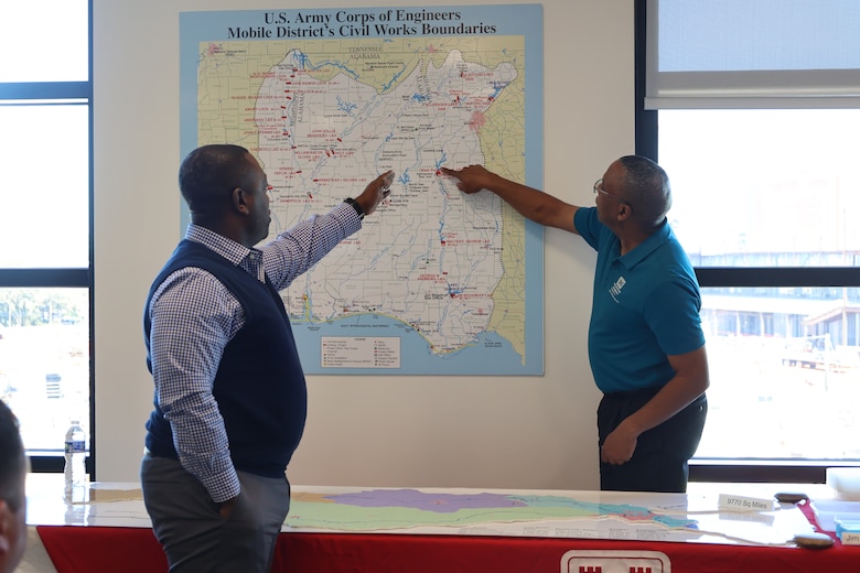 Two men point at a board