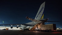 Airmen load cargo into an aircraft at night.