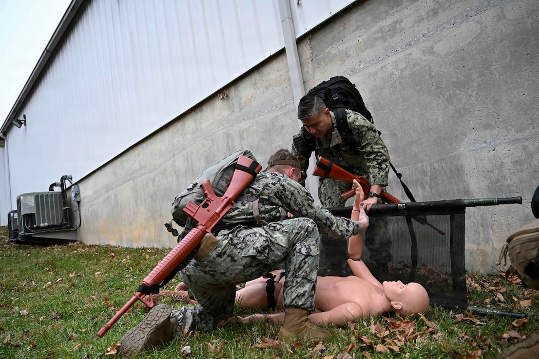 BETHESDA, Md. (Dec. 08, 2025) – Lt. Simon Choi, Assistant Service Chief for the Medical Intensive Care Unit, at Walter Reed National Military Medicine Center (WRNMMC), right, and Hospital Corpsman 3rd Class Evan Selinger, left, assigned both assigned to Navy Medical Readiness and Training Command (NMRTC) Bethesda, provide emergency care as part of the Tactical Combat Casualty Care course testing. The testing marks the culmination of the 63-hour TCCC Combat Medic/Corpsman course, which prepares Navy corpsmen and other military medical personnel to deliver lifesaving trauma care in austere, forward-deployed, and combat environments. NMRTC Bethesda mission is to maximize warfighter performance through optimized medical readiness tailored to operational requirements; enhance the readiness of the medical force to sustain expeditionary medical capability; and train and develop the Navy Medicine Force. (U.S. Navy photo by Mass Communication Specialist 2nd Class Alec Kramer)