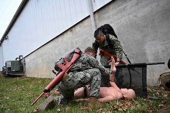 BETHESDA, Md. (Dec. 08, 2025) – Lt. Simon Choi, Assistant Service Chief for the Medical Intensive Care Unit, at Walter Reed National Military Medicine Center (WRNMMC), right, and Hospital Corpsman 3rd Class Evan Selinger, left, assigned both assigned to Navy Medical Readiness and Training Command (NMRTC) Bethesda, provide emergency care as part of the Tactical Combat Casualty Care course testing. The testing marks the culmination of the 63-hour TCCC Combat Medic/Corpsman course, which prepares Navy corpsmen and other military medical personnel to deliver lifesaving trauma care in austere, forward-deployed, and combat environments. NMRTC Bethesda mission is to maximize warfighter performance through optimized medical readiness tailored to operational requirements; enhance the readiness of the medical force to sustain expeditionary medical capability; and train and develop the Navy Medicine Force. (U.S. Navy photo by Mass Communication Specialist 2nd Class Alec Kramer)