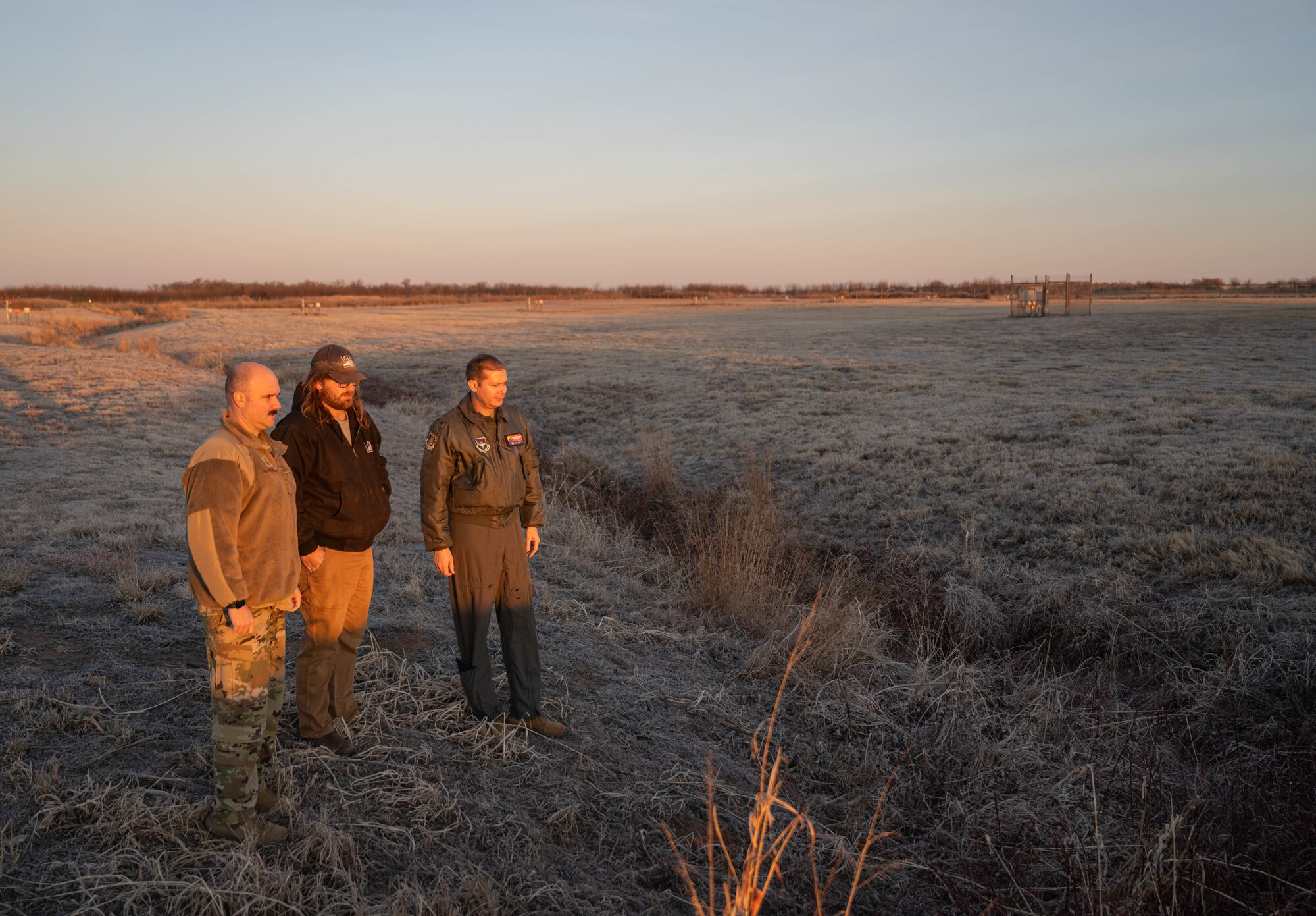 U.S. Air Force Chief Master Sgt. Jonny Adams, 97th Air Mobility Wing (AMW) command chief, left, Mitchell Singer, U.S. Department of Agriculture wildlife biologist, center, and U.S. Air Force Col. Richard Kind, 97th AMW commander, right, observe a drainage ditch at Altus Air Force Base, Oklahoma, Feb. 5, 2026. Throughout the immersion tour, Singer highlighted specific areas of concern such as 10-foot drainage ditches, essential for water management, yet attractive hiding spots for small wildlife that can quickly become a danger during flight operations. (U.S. Air Force photo by Airman 1st Class Emma Wright)