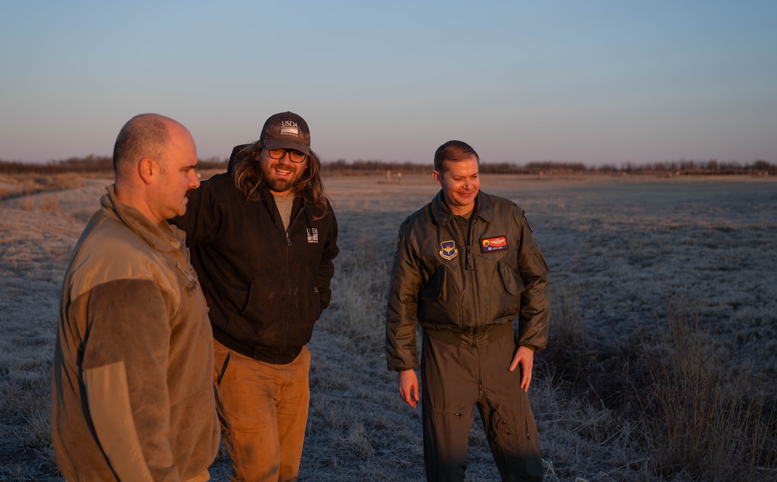 U.S. Air Force Chief Master Sgt. Jonny Adams, 97th Air Mobility Wing (AMW) command chief, left, Mitchell Singer, U.S. Department of Agriculture (USDA) wildlife biologist, center, and U.S. Air Force Col. Richard Kind, 97th AMW commander, right, discuss wildlife mitigation at Altus Air Force Base, Oklahoma, Feb. 5, 2026. The immersion tour traced the outer and inner perimeter loops of the installation, observing the full scope of the USDA wildlife specialists’ pre-flight inspection process. (U.S. Air Force photo by Airman 1st Class Emma Wright)