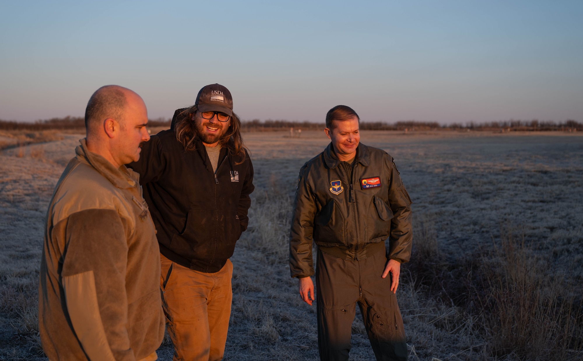 U.S. Air Force Chief Master Sgt. Jonny Adams, 97th Air Mobility Wing (AMW) command chief, left, Mitchell Singer, U.S. Department of Agriculture (USDA) wildlife biologist, center, and U.S. Air Force Col. Richard Kind, 97th AMW commander, right, discuss wildlife mitigation at Altus Air Force Base, Oklahoma, Feb. 5, 2026. The immersion tour traced the outer and inner perimeter loops of the installation, observing the full scope of the USDA wildlife specialists’ pre-flight inspection process. (U.S. Air Force photo by Airman 1st Class Emma Wright)