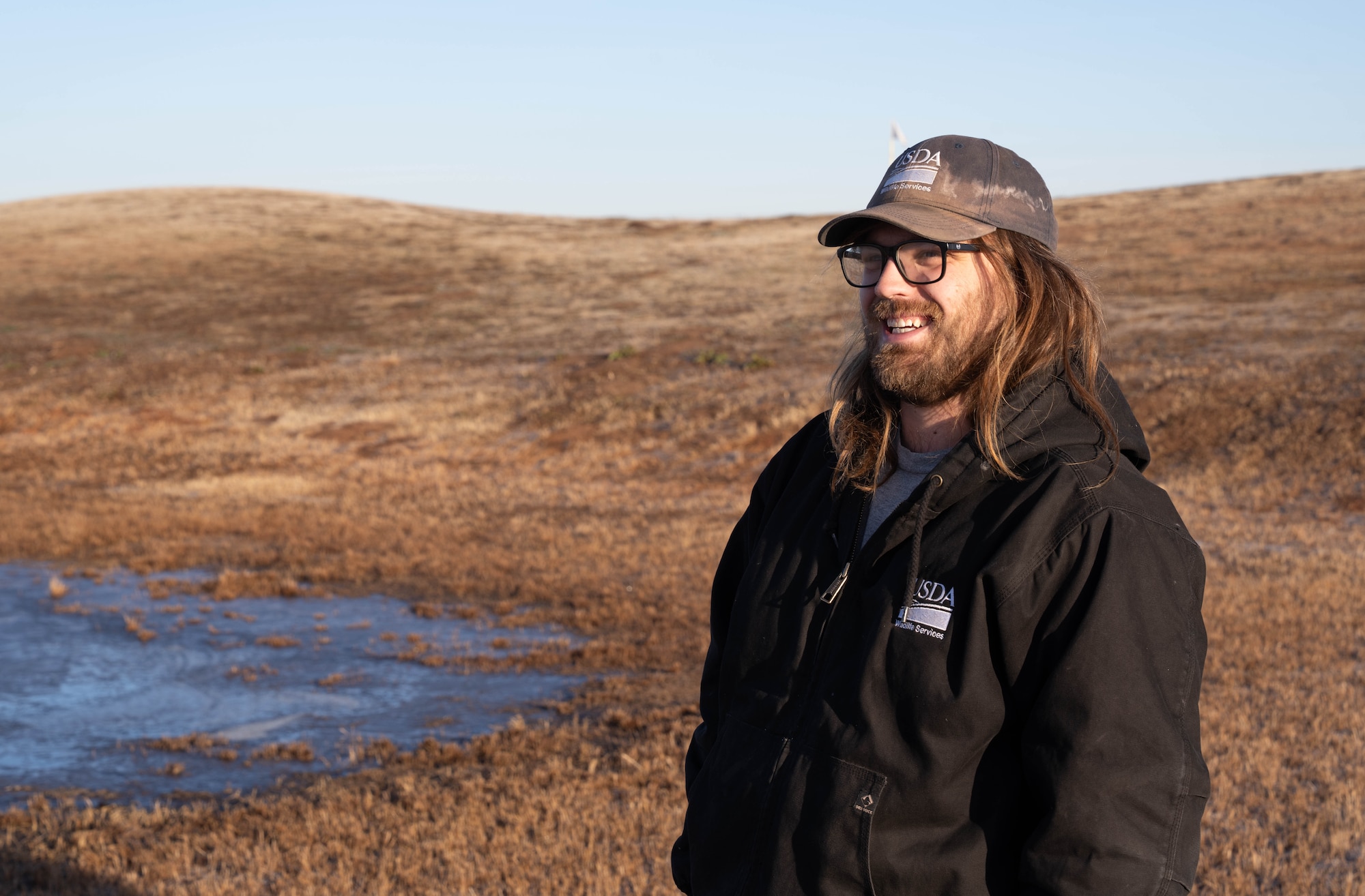 Mitchell Singer, U.S. Department of Agriculture (USDA) wildlife biologist, smiles at Altus Air Force Base (AFB), Oklahoma, Feb. 5, 2026. By stepping into the daily operations of the safety team and USDA wildlife specialists, the 97th Air Mobility Wing command team gained a deeper understanding for how proactive wildlife mitigation enables Altus AFB to continue delivering superior mobility aircrew training. (U.S. Air Force photo by Airman 1st Class Emma Wright)