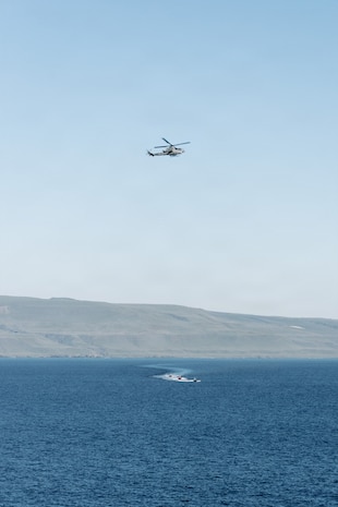An AH-1Z Viper with Marine Medium Tiltrotor Squadron (VMM) 163 (Reinforced), 11th Marine Expeditionary Unit, flies over simulated adversary vessels approaching San Antonio-class amphibious transport dock ship USS Portland (LPD 27) during a simulated strait transit in the Pacific Ocean, Jan. 27, 2026. The simulated strait transit was conducted to refine the 11th Marine Expeditionary Unit’s ability to integrate with the Navy for enhanced force protection. The 11th MEU is currently underway aboard the Boxer Amphibious Ready Group in the U.S. 3rd Fleet area of operations conducting integrated training that enhances lethality and warfighting readiness. (U.S. Marine Corps photo by Lance Cpl. Luke Rodriguez)