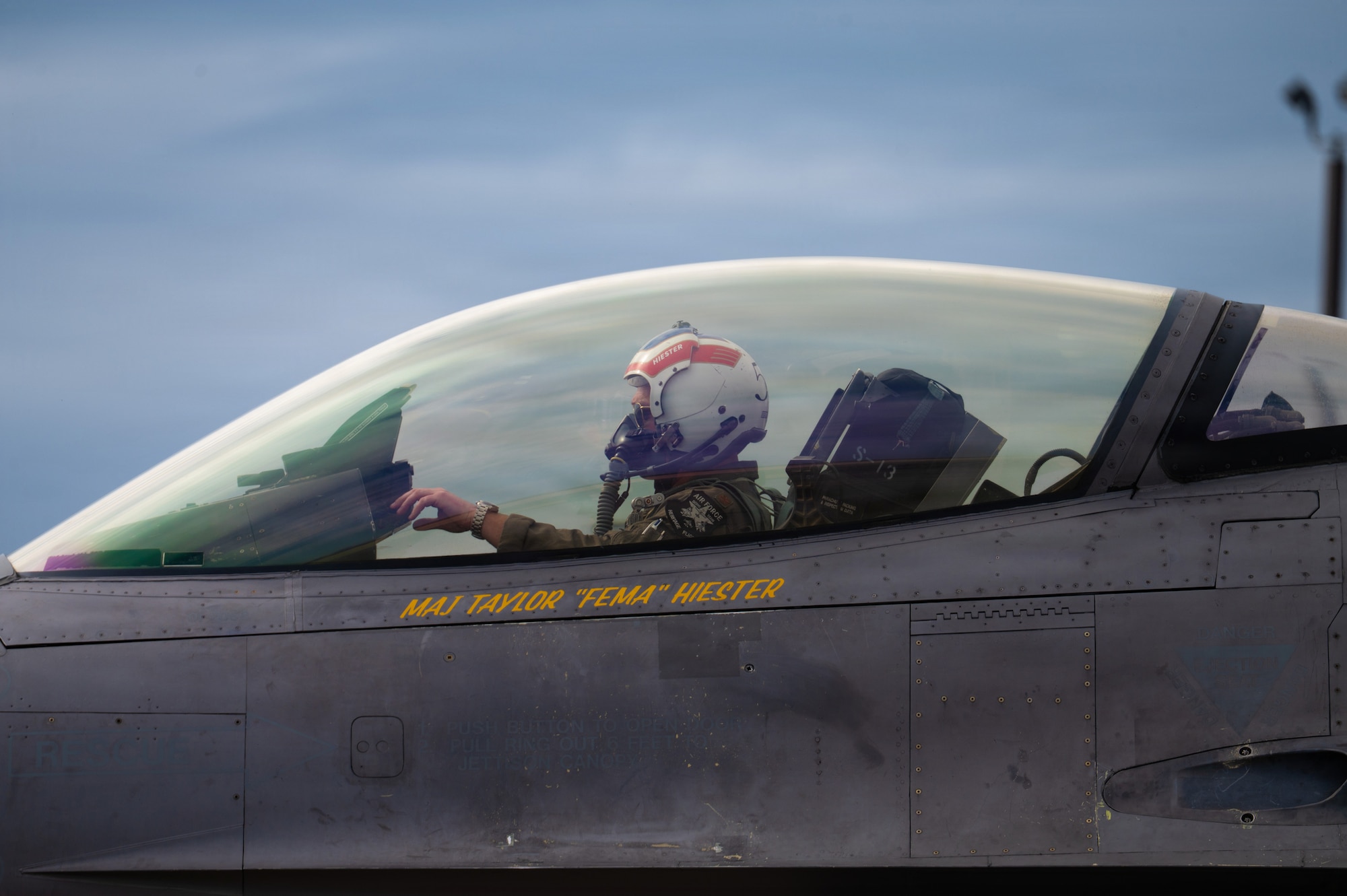 A fighter pilot touches a console in front of him as he sits in his fighter jet