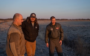 U.S. Air Force Chief Master Sgt. Jonny Adams, 97th Air Mobility Wing (AMW) command chief, left, Mitchell Singer, U.S. Department of Agriculture (USDA) wildlife biologist, center, and U.S. Air Force Col. Richard Kind, 97th AMW commander, right, discuss wildlife mitigation at Altus Air Force Base, Oklahoma, Feb. 5, 2026. The immersion tour traced the outer and inner perimeter loops of the installation, observing the full scope of the USDA wildlife specialists’ pre-flight inspection process. (U.S. Air Force photo by Airman 1st Class Emma Wright)