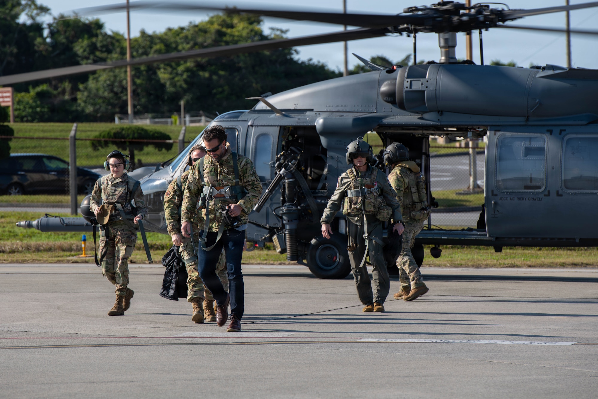 Government official and service members step off helicopter.