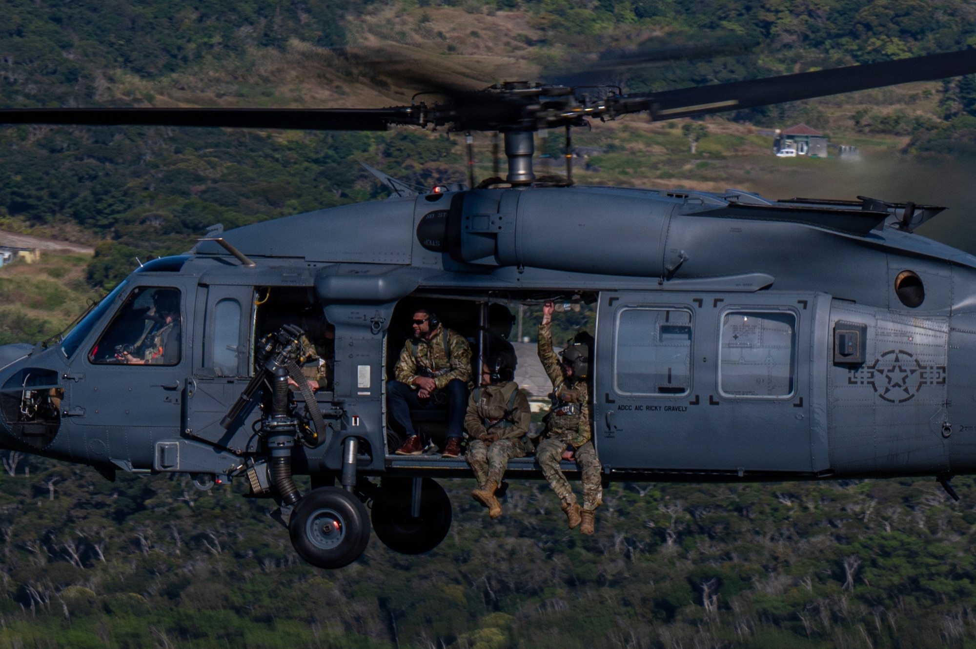 Government official and service members fly on helicopter for aerial tour.