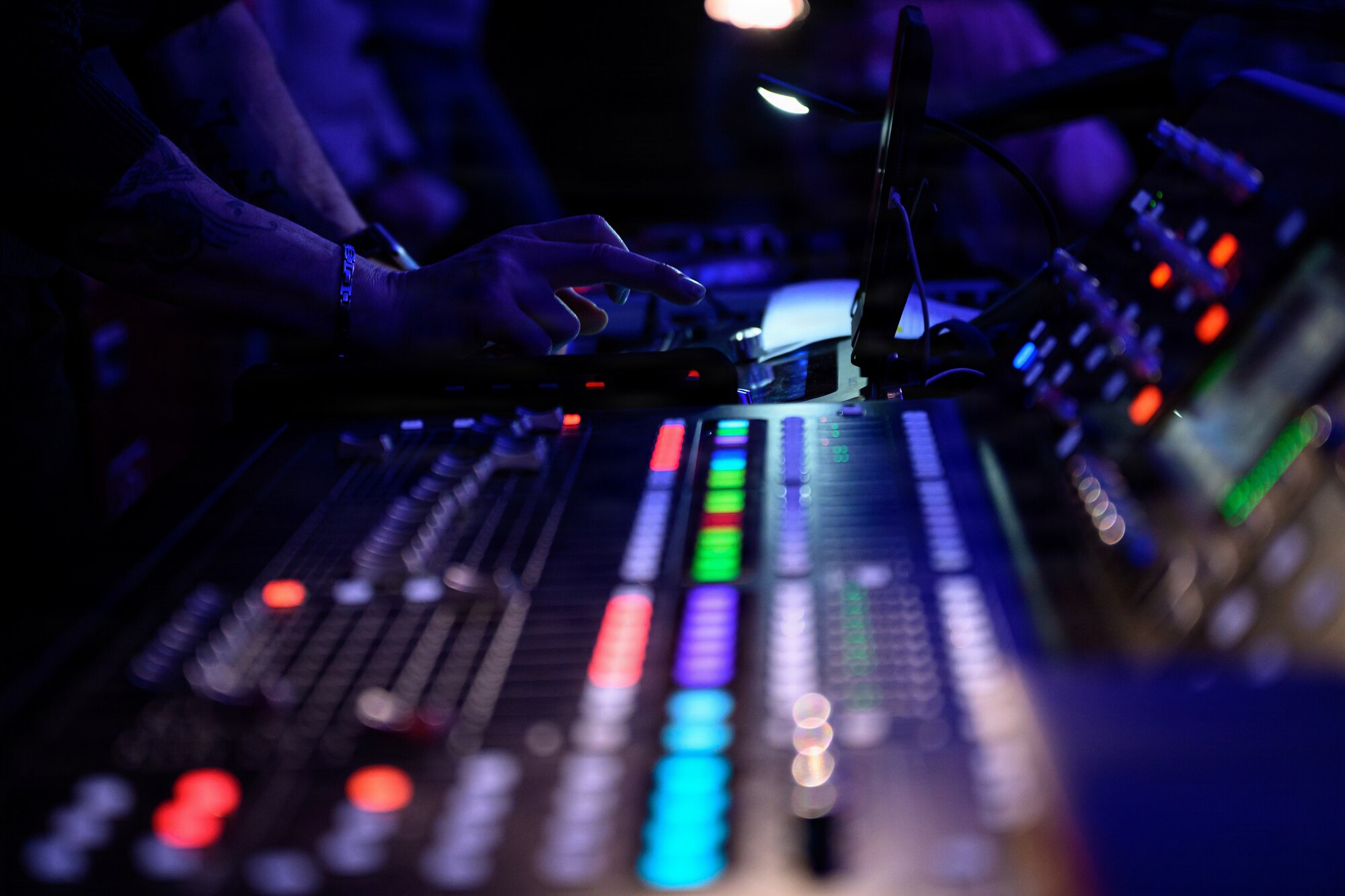 A DJ presses buttons on a colorful DJ table.