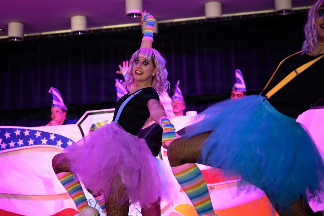 A group of dancers dressed as clowns dance on stage.