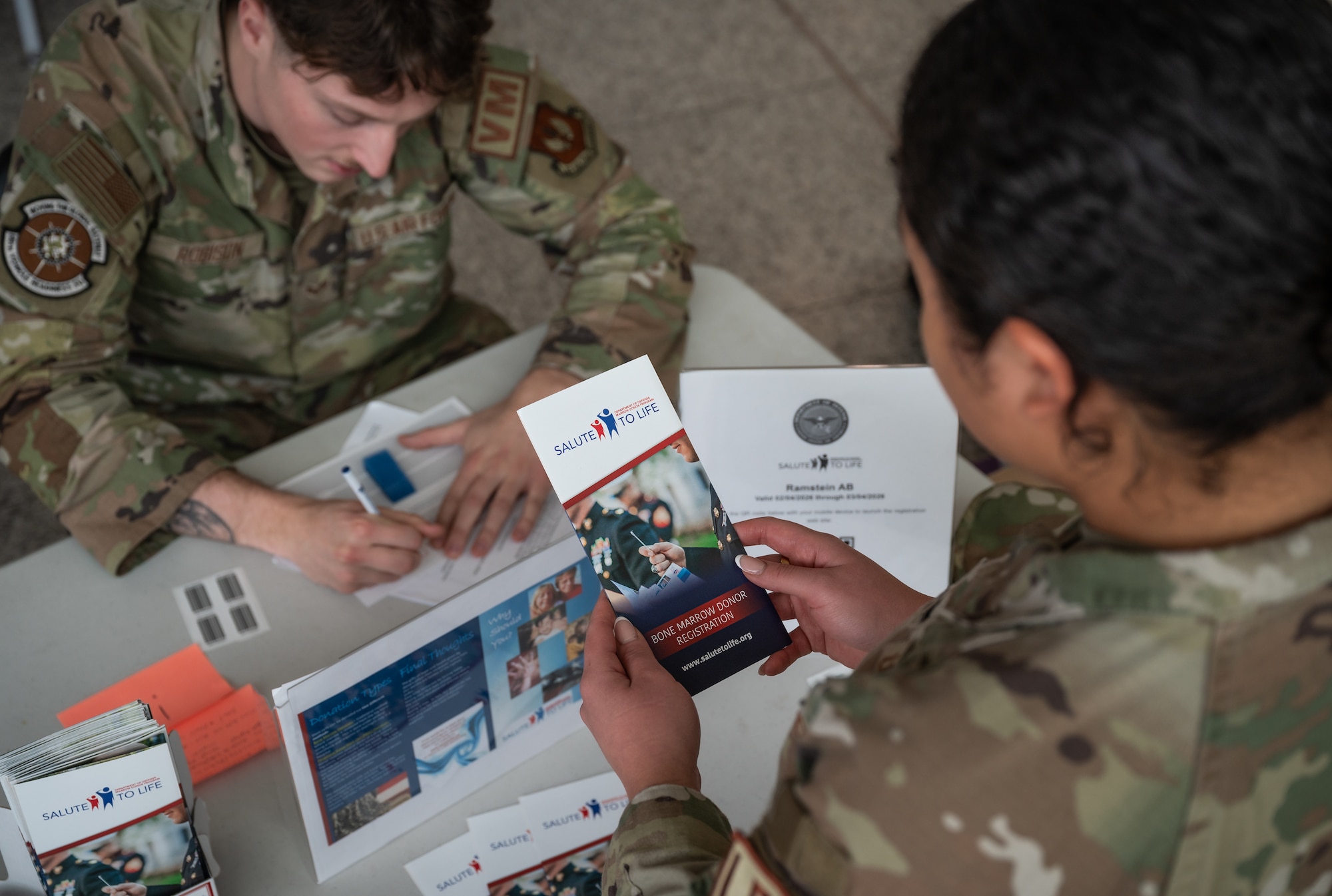 U.S. Air Force 1st Lt. Ira Frazier, 86th Logistics Readiness Squadron military installation deployment officer, looks at a brochure for the Salute to Life Program at Ramstein Air Base, Germany, Feb. 10, 2026. The Salute to Life program allows individuals to join the National Marrow Donor Registry through a brief consent process and cheek swab. (U.S. Air Force photo by Senior Airman Jared Lovett)