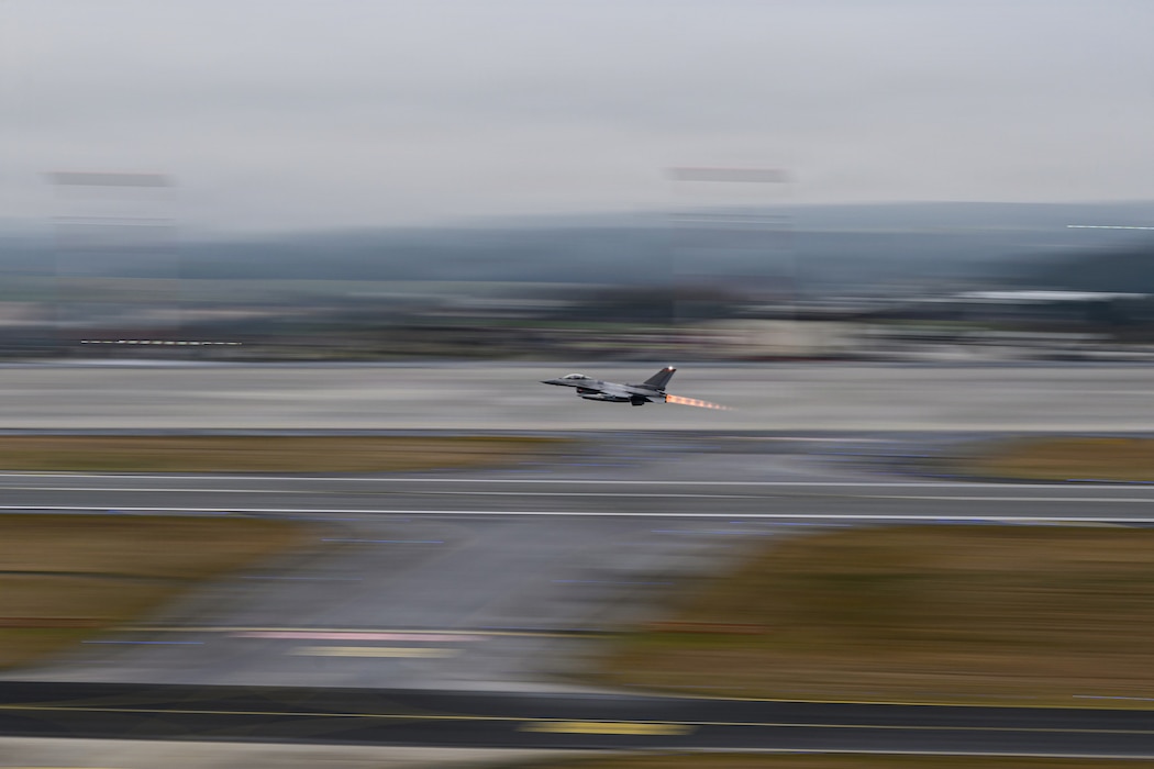 A fighter aircraft takes off from a runway at an air base.