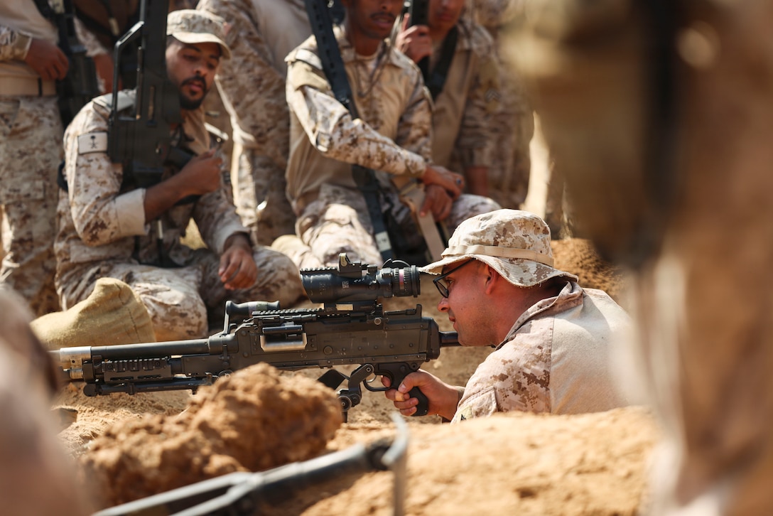 A U.S. Marine assigned to Fleet Anti-Terrorism Security Team Central Command, demonstrates an M240B machine gun fighting position to Saudi marines with the Royal Saudi Naval Forces during exercise Indigo Defender 26 at King Faisal Naval Base, Saudi Arabia, Feb. 3, 2026. Indigo Defender 26 is a capstone bilateral maritime exercise between Royal Saudi Naval Forces and U.S. Naval Forces Central Command to enhance interoperability and strengthen our capacity to maintain regional maritime security and stability.  (U.S. Marine Corps photo by Sgt. Angela Wilcox)