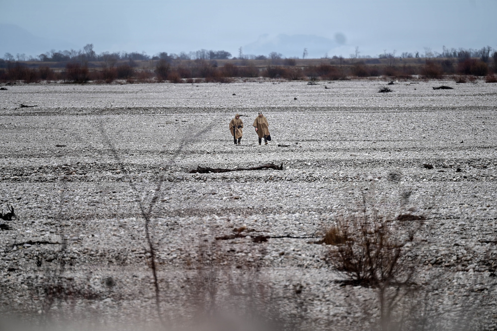 Servicemembers walking through a riverbed.