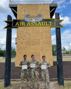 U.S. Air Force (from left to right), Senior Airman James Daniels, a patrolman with the 11th Security Forces Squadron, Staff Sgt. Zachary Lee Artibee, non-commissioned officer in charge of research and analysis with the 11th SFS, and 2nd Lt. Juan Garcia, flight commander for the 11th SFS, pose in front of the Air Assault Wall at the U.S. Army’s Sabalauski Air Assault School, Fort Campbell, Tenn., Sept. 1, 2025. These Airmen earned the U.S. Army’s Air Assault Badge, which focused on combat and air operations over 10 days of instruction. The course included tactical training, rappelling, written assessments and a 12-mile ruck march. (Courtesy photo provided by U.S. Air Force Staff Sergeant Zachary Artibee)