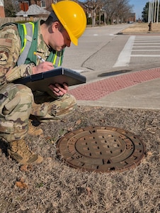 Airman observes manhole cover.
