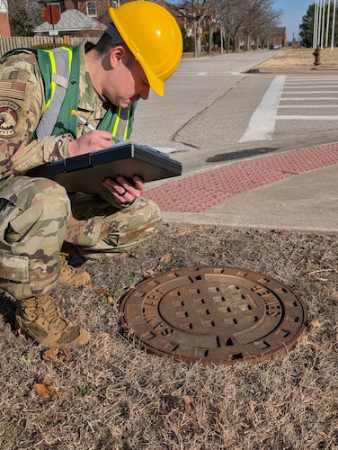 Airman observes manhole cover.