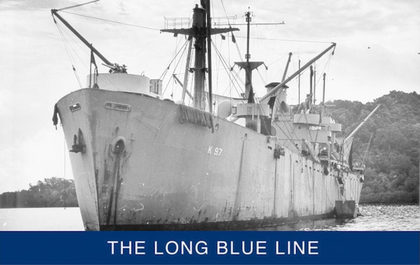 USS Serpens at anchor somewhere in the Pacific islands with derricks extended to take on cargo. (U.S. Navy)