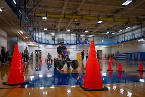 Members of Team McConnell navigate a non-motorized vehicle through a course while wearing impairment simulation goggles during Tanker Talks 2.0 at McConnell Air Force Base, Feb. 9, 2026. The activity was designed to demonstrate how alcohol and THC-related impairment can affect coordination, reaction time and decision-making in a controlled environment. (U.S. Air Force photo by Senior Airman Paula Arce)