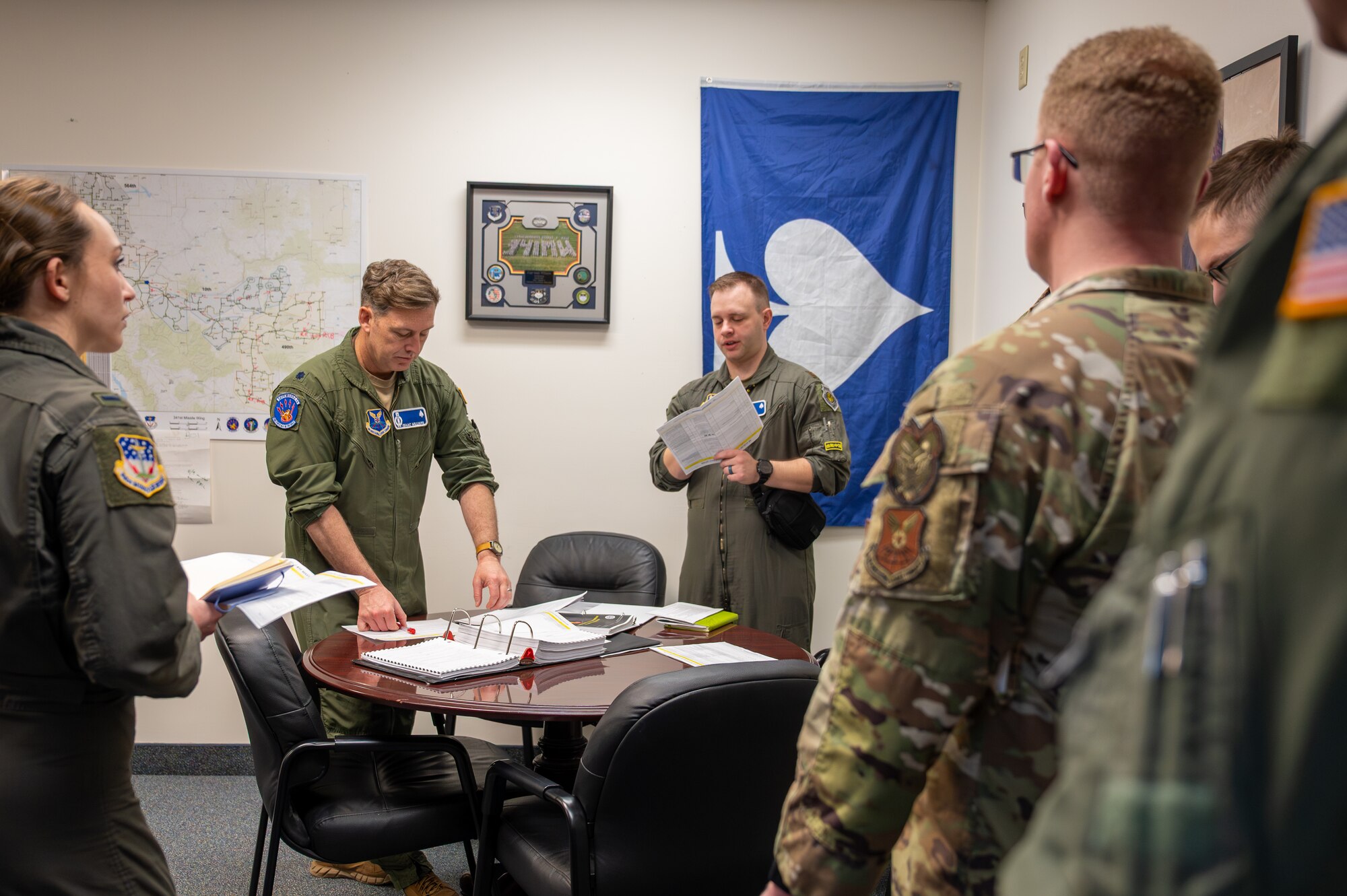 A group of uniformed personnel stand around a table.