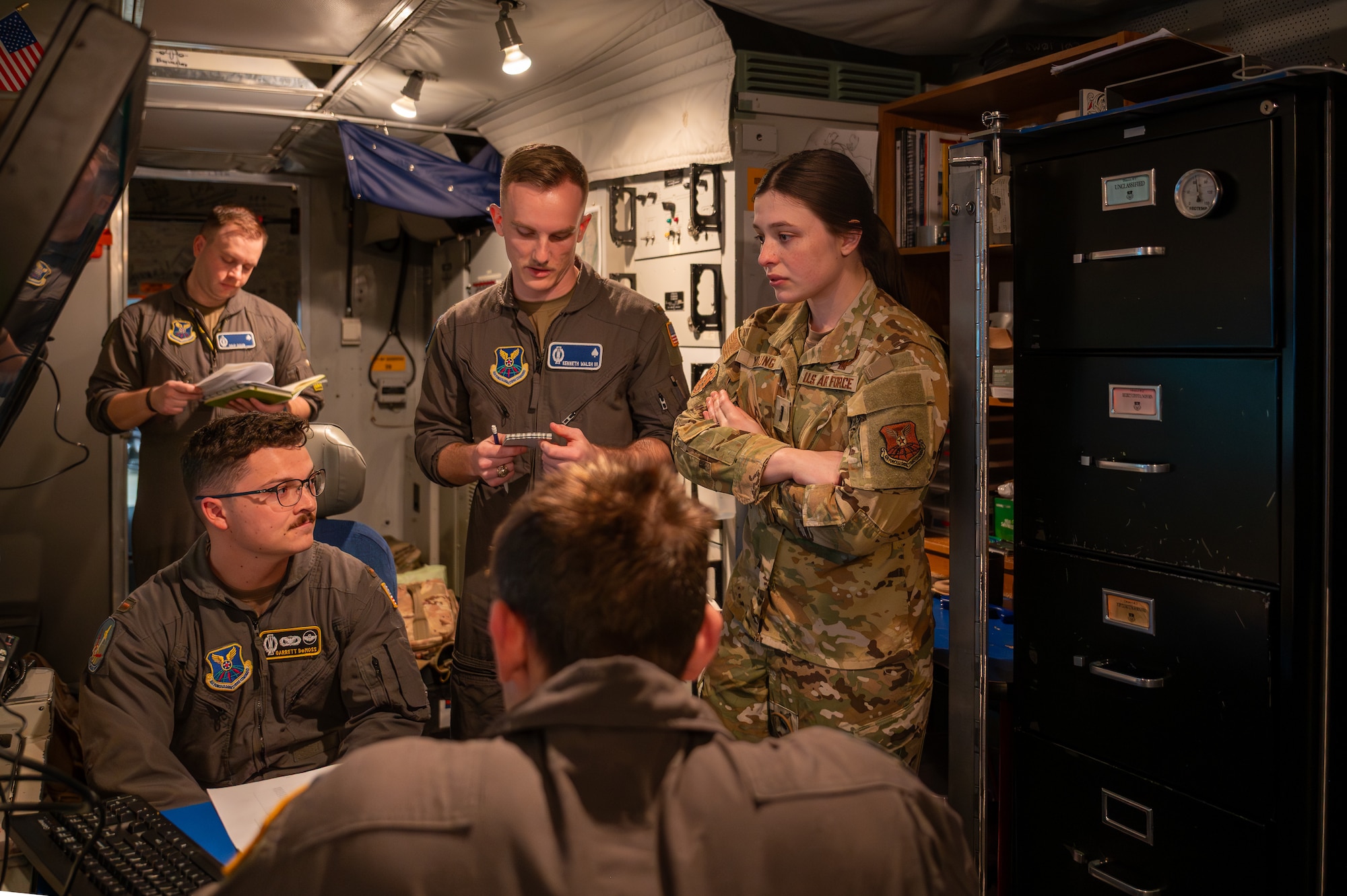 A group of uniformed personnel stand around a table.