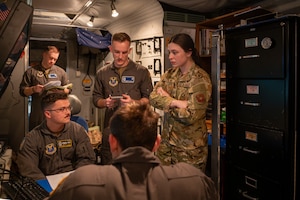 A group of uniformed personnel stand around a table.